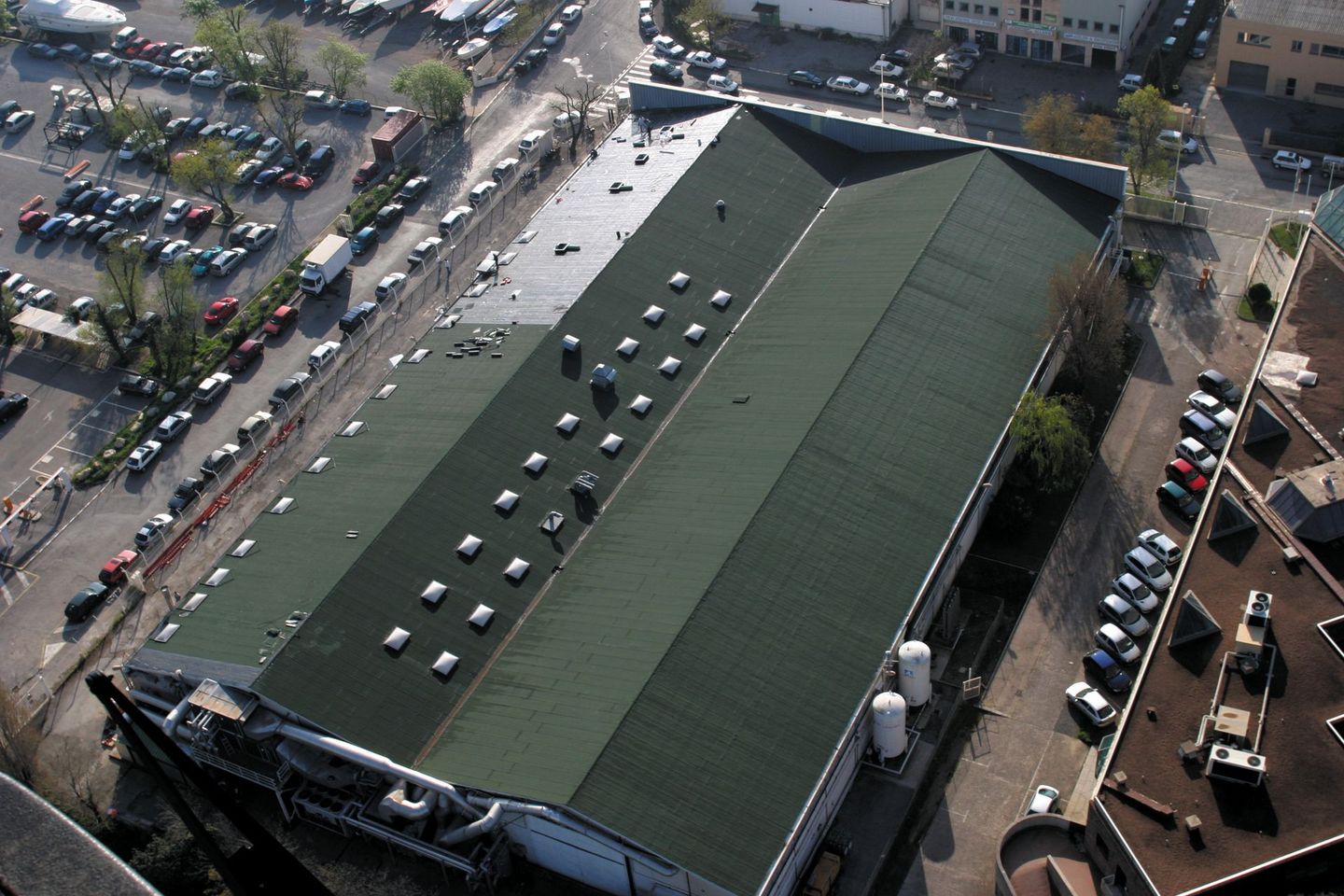 Vue aérienne d'un toit plat et gris avec des rambardes de sécurité, avec des arbres verts en arrière-plan.