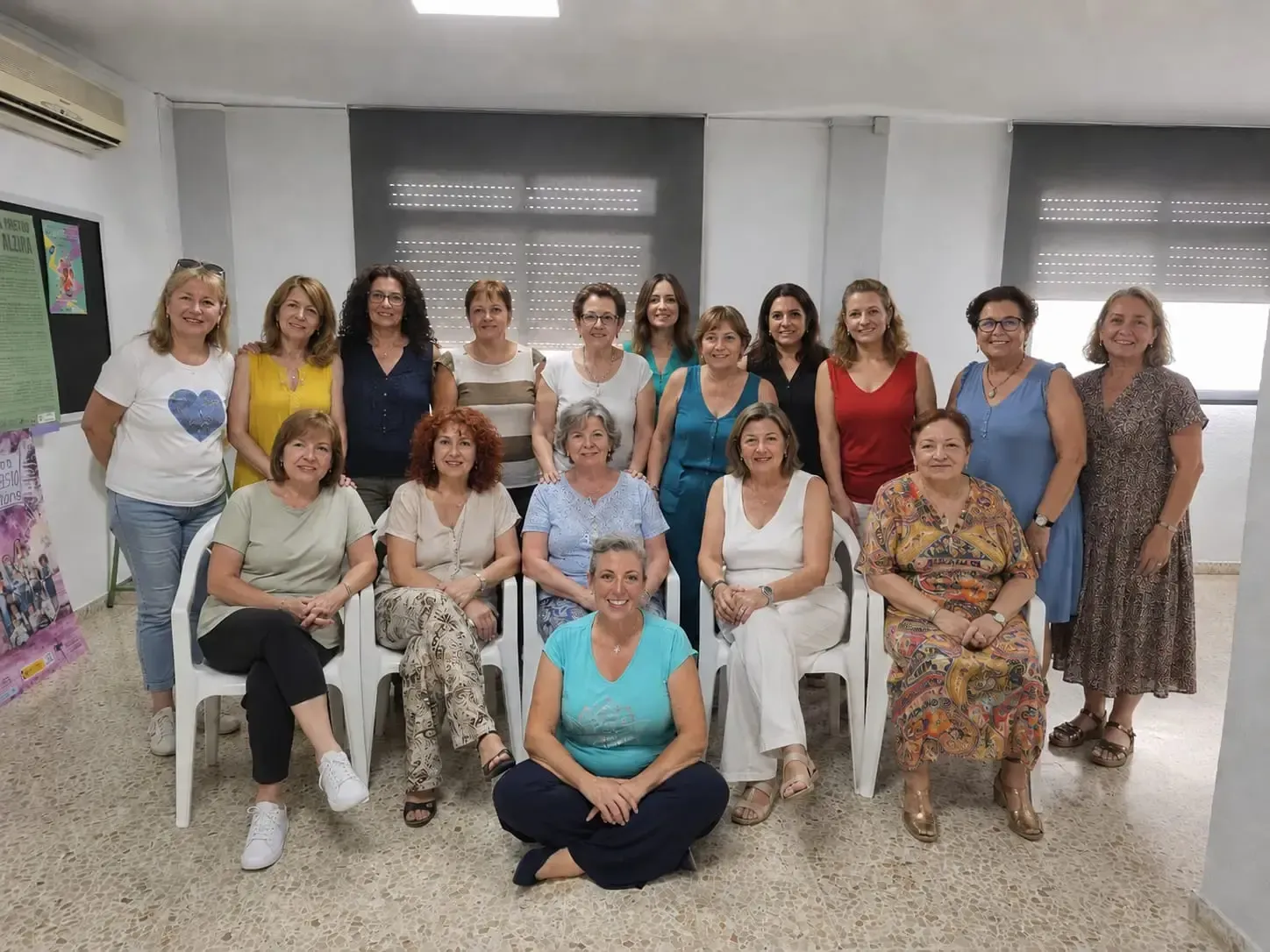 Grupo de personas posando juntas en un espacio interior, unas sentadas y otras de pie, en una sala luminosa.