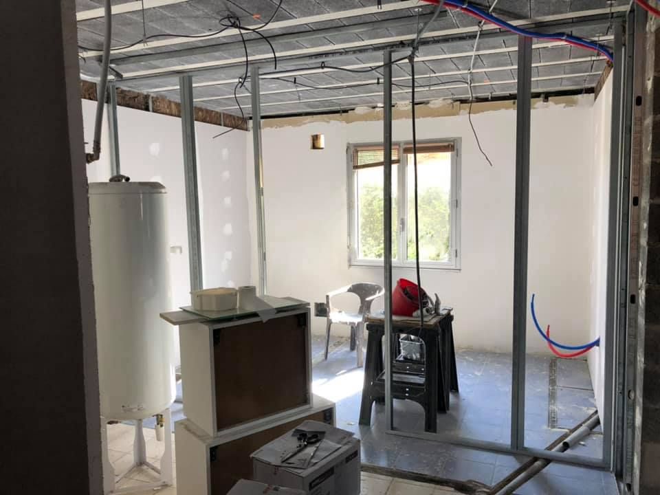 Pièce intérieure en construction avec charpente métallique, chauffe-eau et murs non finis