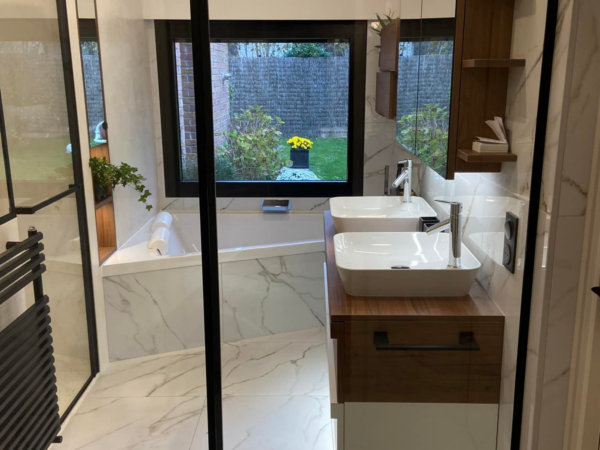 Salle de bains moderne avec carrelage en marbre, double vasque et fenêtre donnant sur un jardin