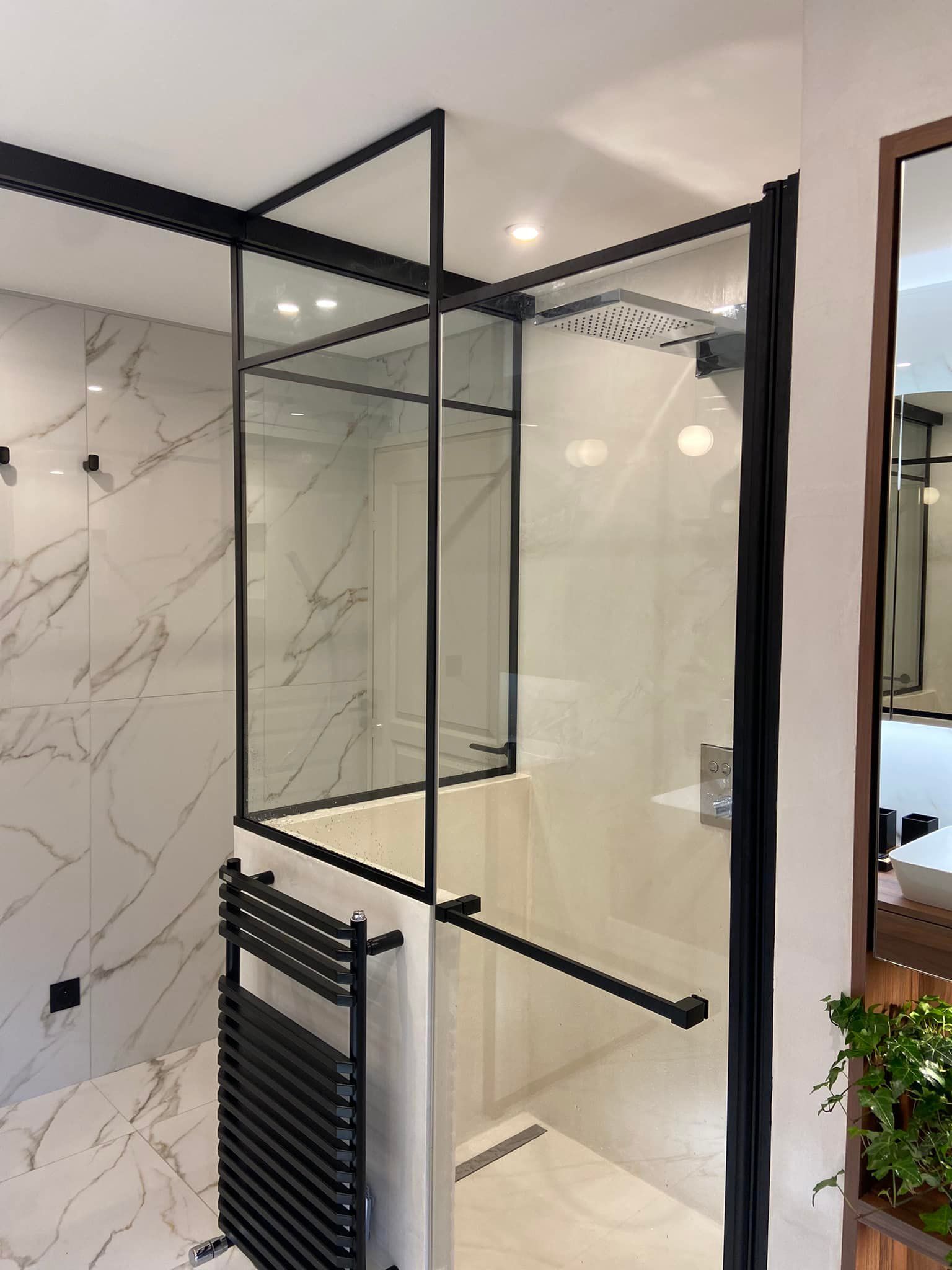 Cabine de douche en verre à cadre noir dans une salle de bains moderne avec carrelage en marbre et porte-serviettes