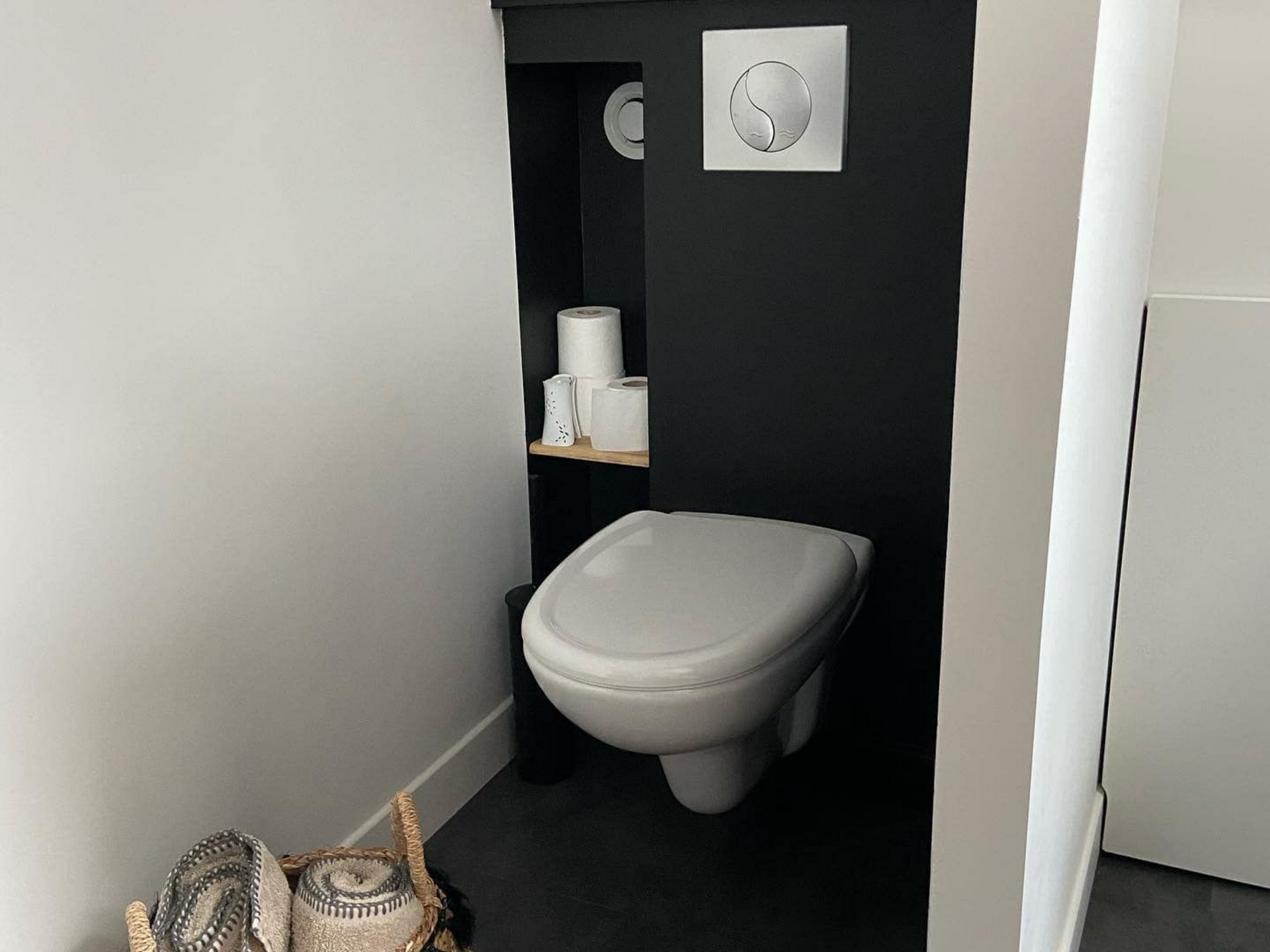 Une petite salle de bains moderne avec des toilettes murales et une étagère pour papier toilette