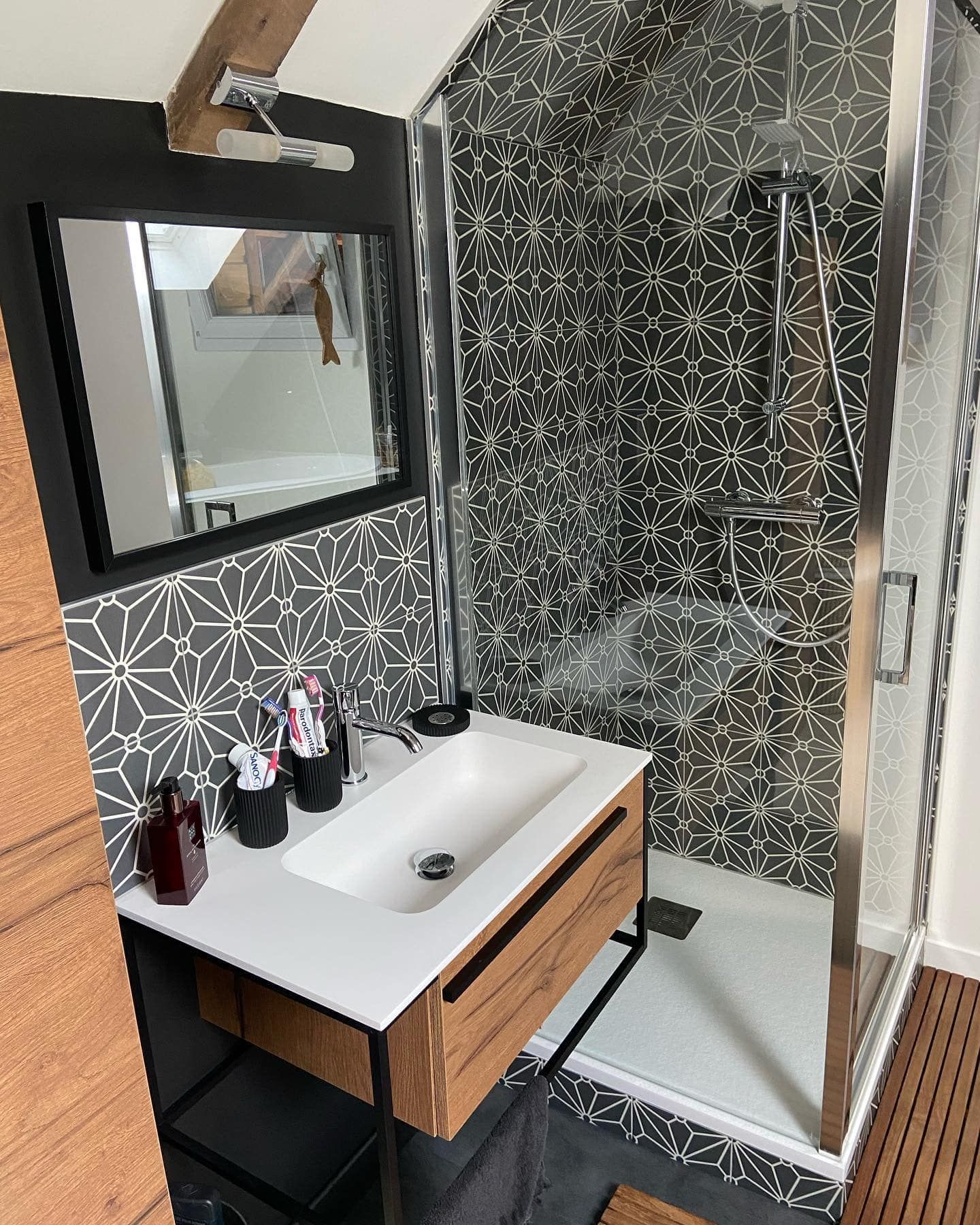 Salle de bains moderne avec carrelage à motifs, vanité flottante et porte de douche en verre