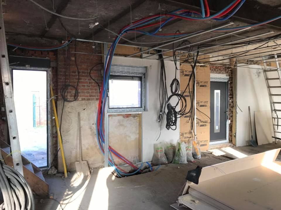 Vue intérieure d'une pièce en construction avec briques apparentes, tuyaux et portes