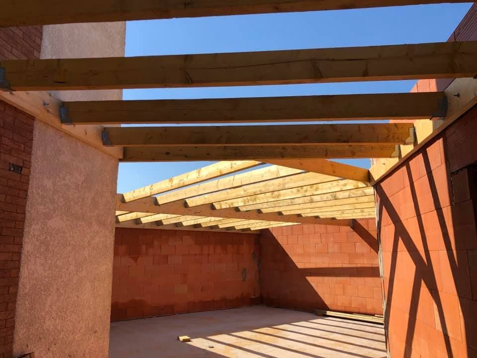 Vue intérieure d'un bâtiment en construction, avec poutres en bois apparentes