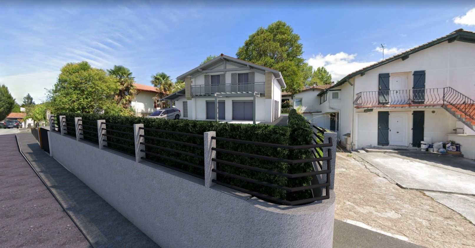 Rue résidentielle tranquille bordée de maisons, d'un mur blanc, d'une clôture noire et de véhicules stationnés par une journée ensoleillée