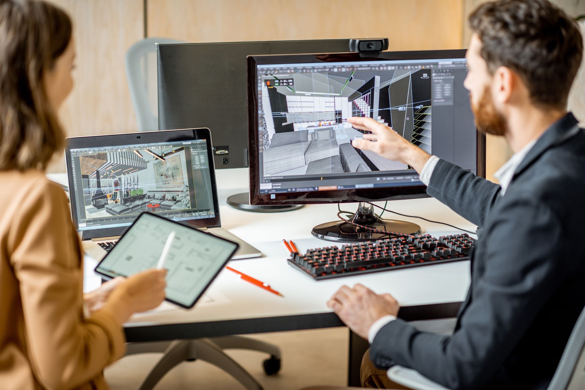 Trois collègues examinent des plans d'architecture sur des ordinateurs portables et un grand écran dans un bureau moderne