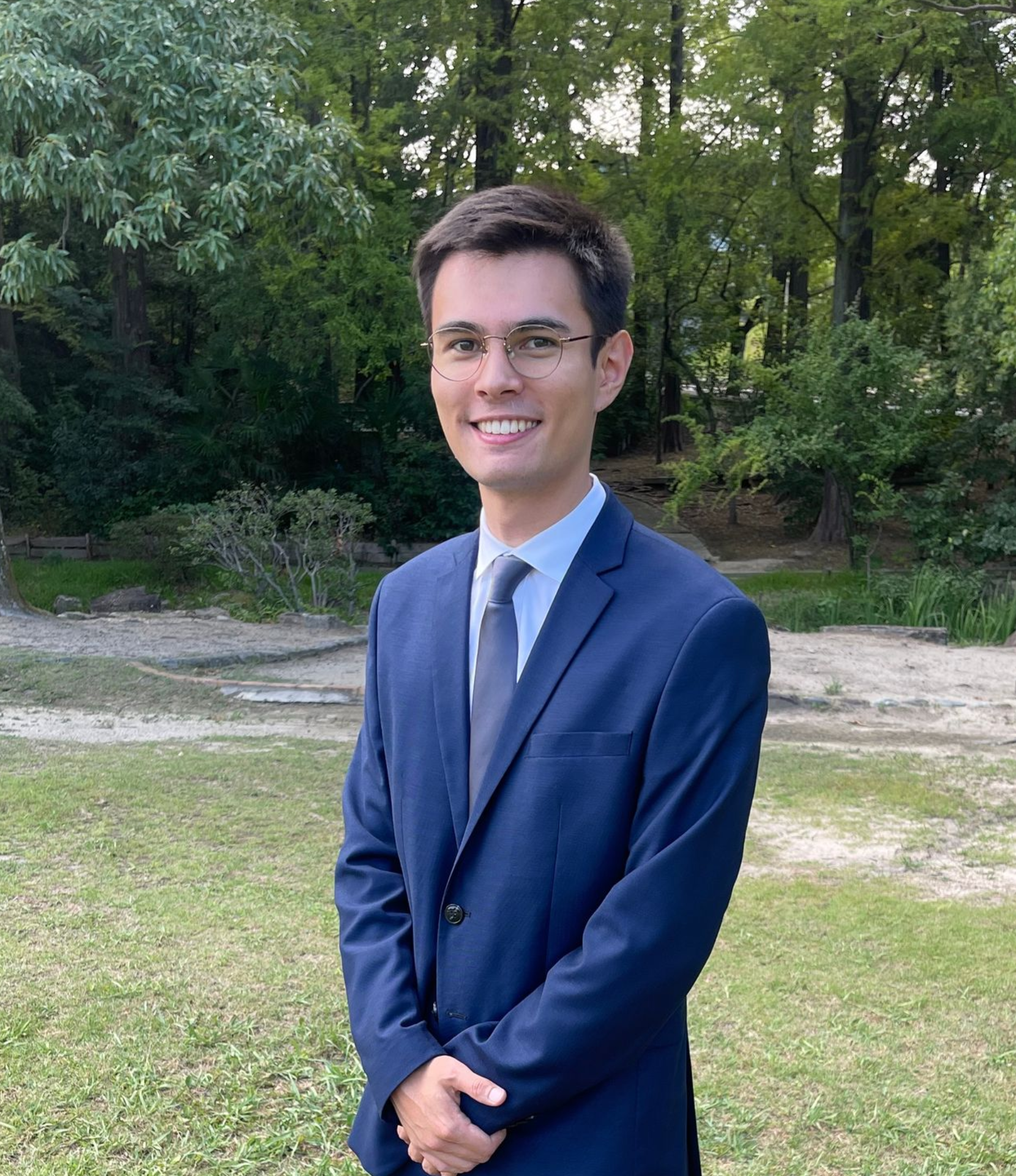 Eine Frau in einer blauen Jacke und einem weißen Hemd steht vor einer Skulptur.