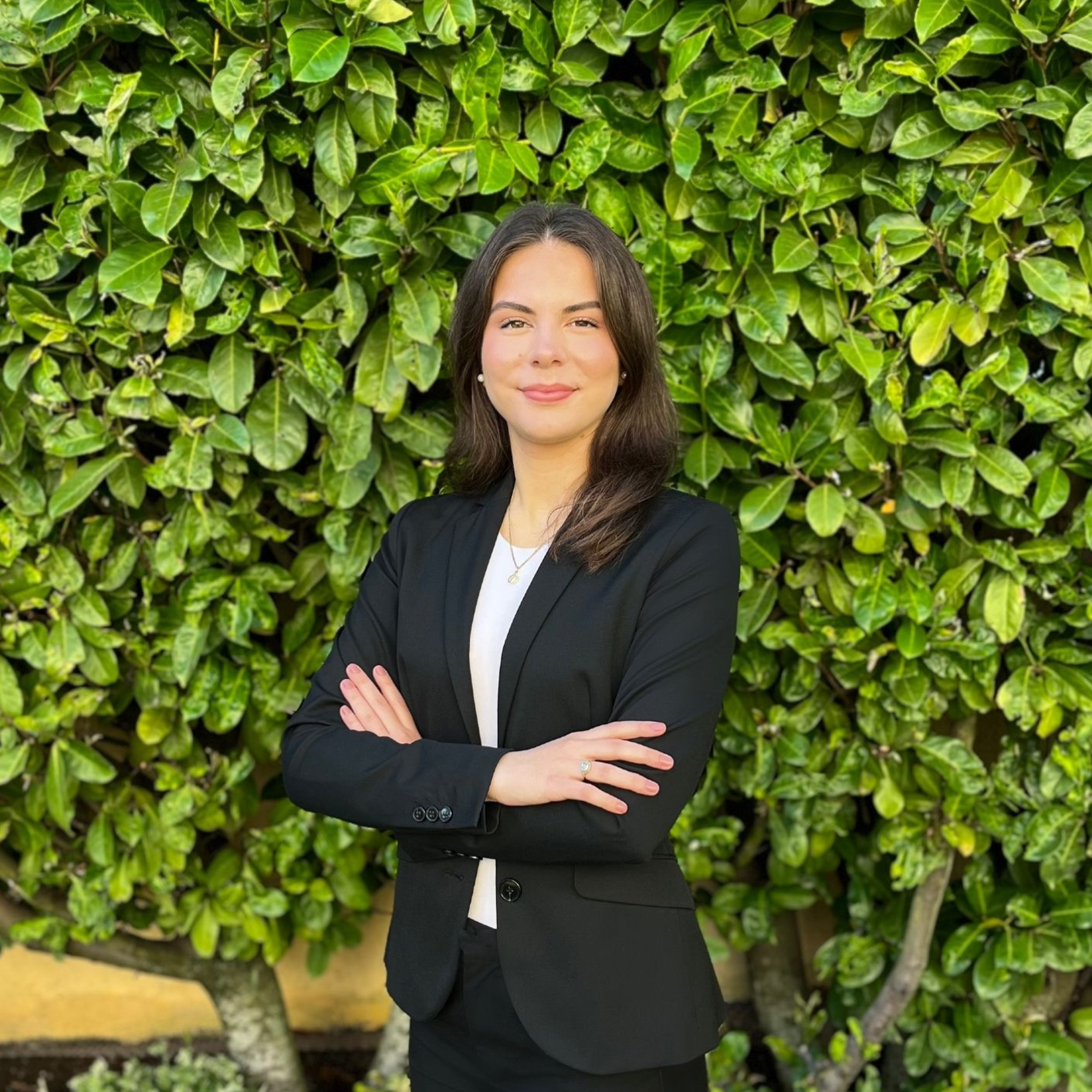 Eine Frau in einer schwarzen Jacke und einem weißen Hemd lächelt in die Kamera.