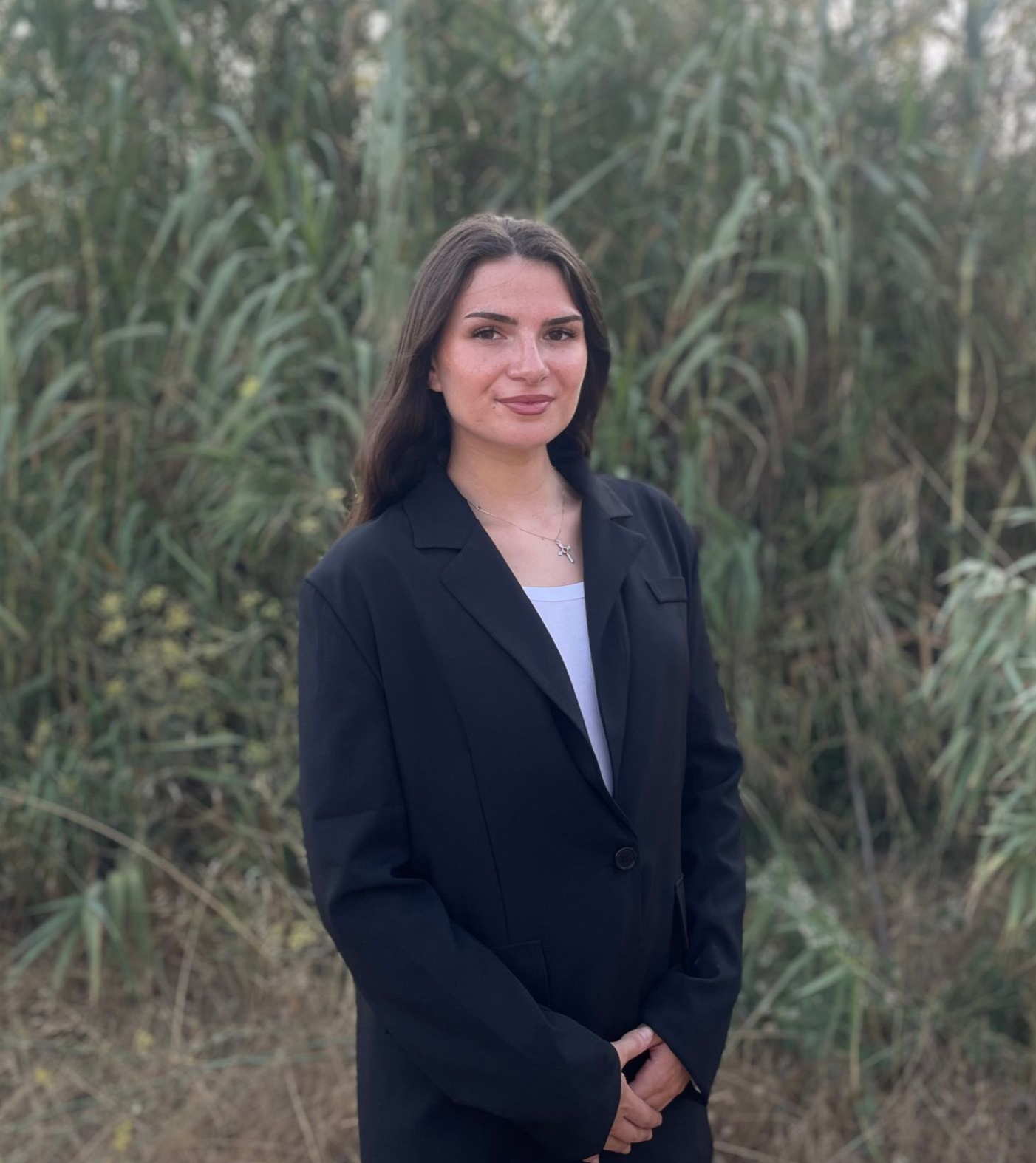 Eine Frau in einer blauen Jacke und einem weißen Hemd lächelt in die Kamera.