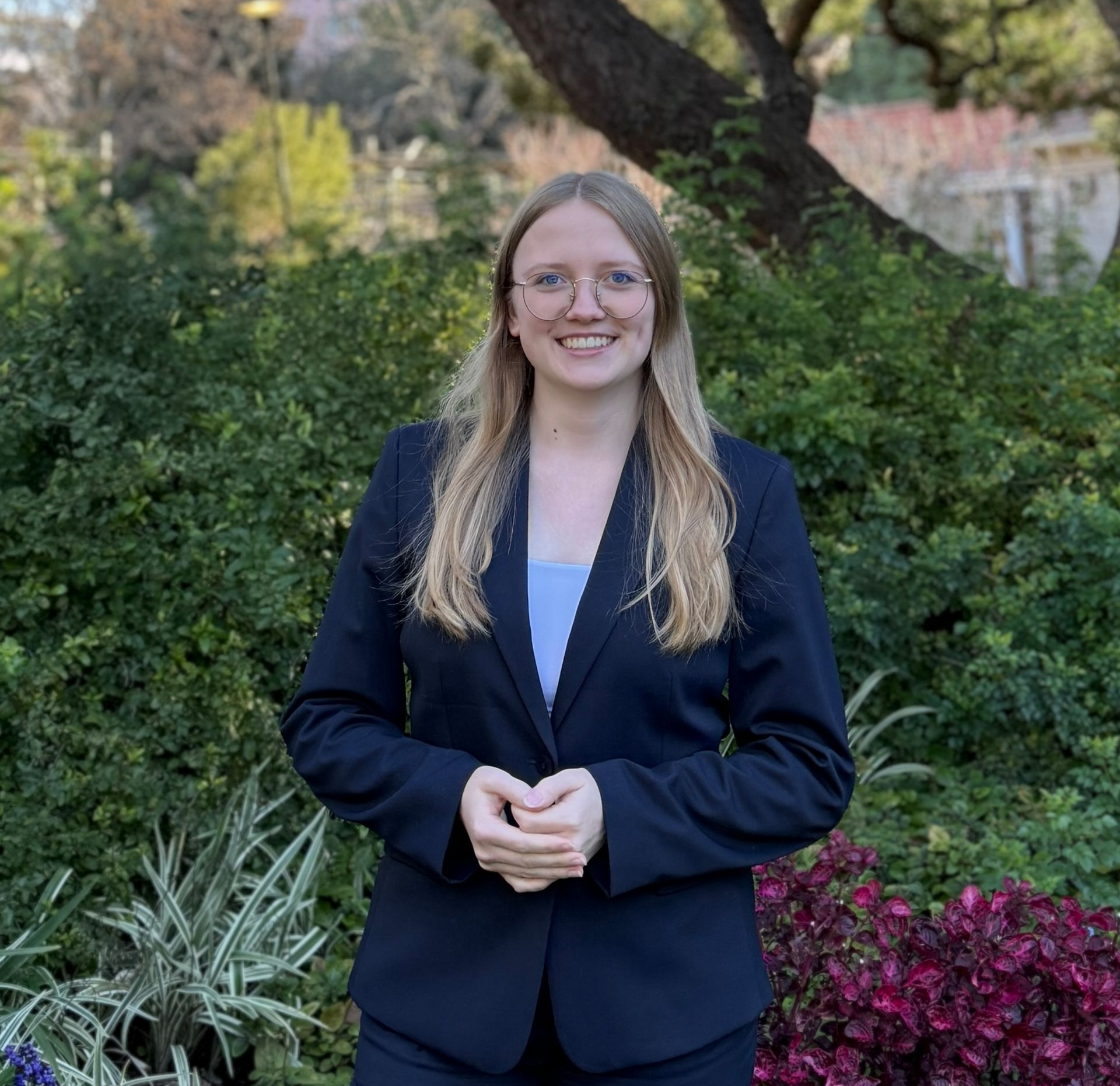 Eine Frau im schwarzen Anzug steht vor einer großen weißen Skulptur.