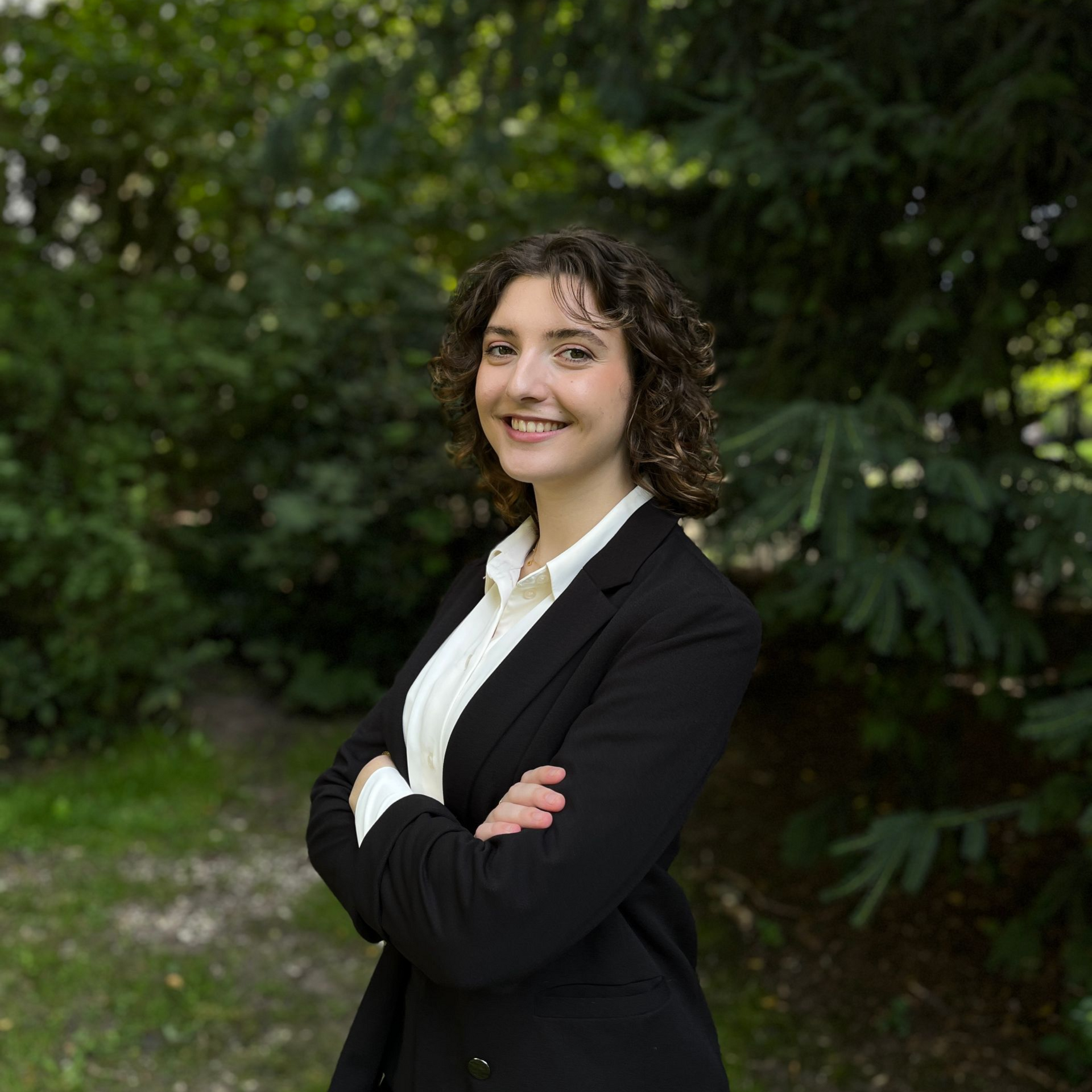 Eine Frau in einer schwarzen Jacke und einem weißen Hemd lächelt in die Kamera.