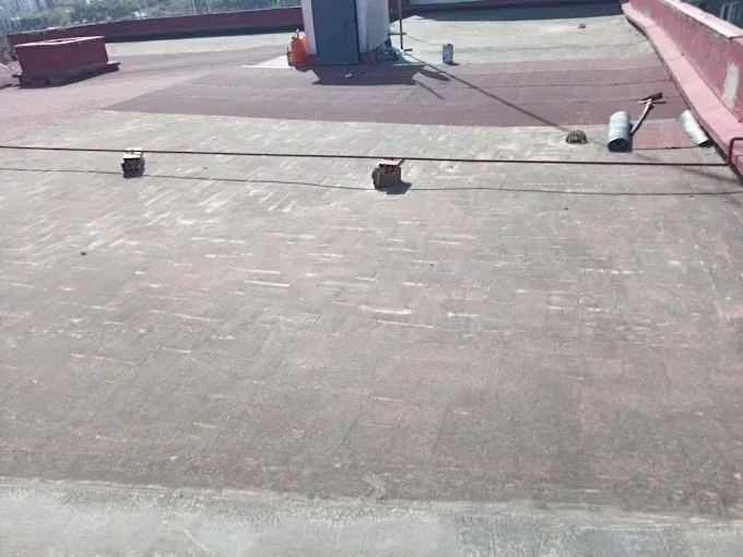 Azotea plana con rejillas de ventilación rojas, tuberías y una claraboya central que recibe luz natural.