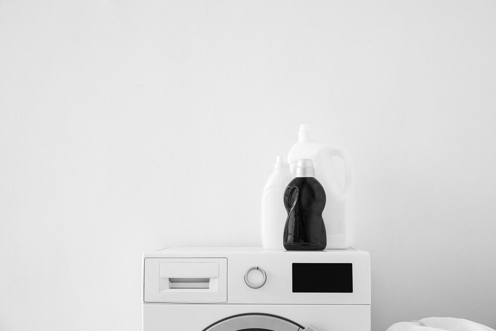 Una lavadora con una botella de detergente para ropa encima.