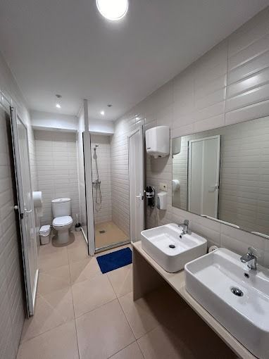 Un baño con dos lavabos, un inodoro y una ducha.