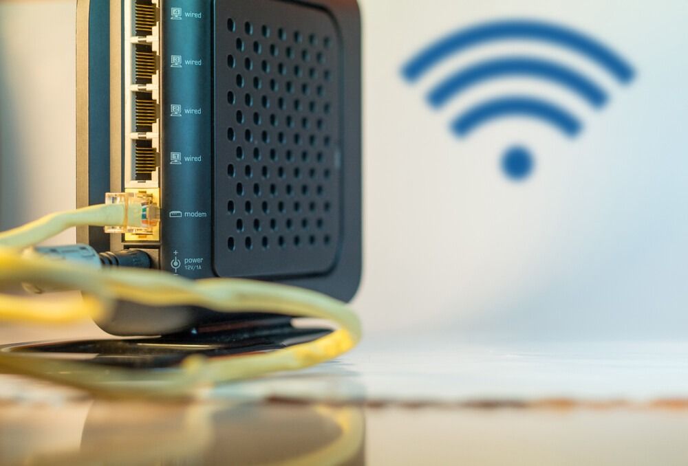 Un primer plano de un enrutador con un símbolo de wifi en el fondo.