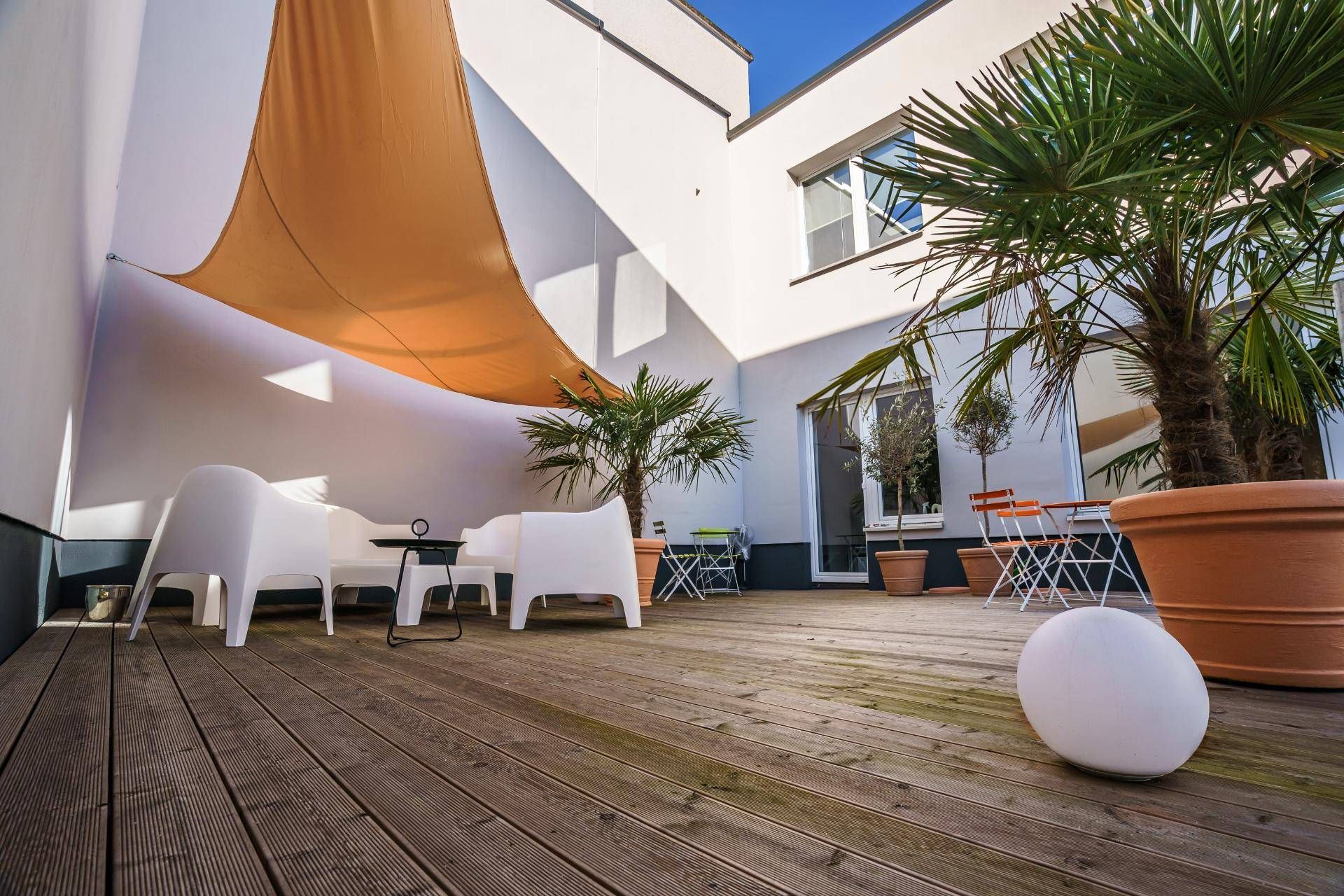 Eine Dachterrasse mit Baldachin, Stühlen, Tischen und Topfpflanzen