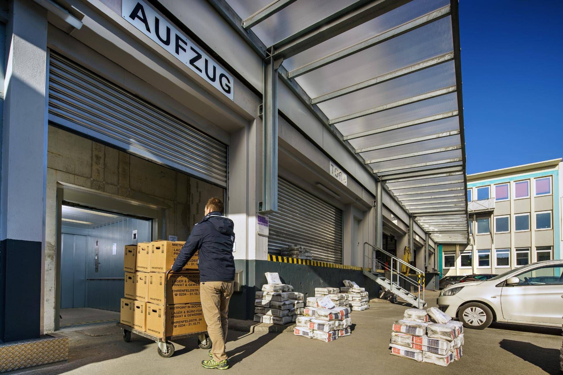 Ein Mann schiebt einen Karren voller Kisten in ein Lagerhaus