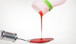 Se vierte una botella de líquido en una cuchara.