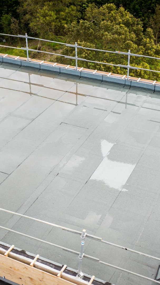 Toit plat et gris avec une rambarde blanche.