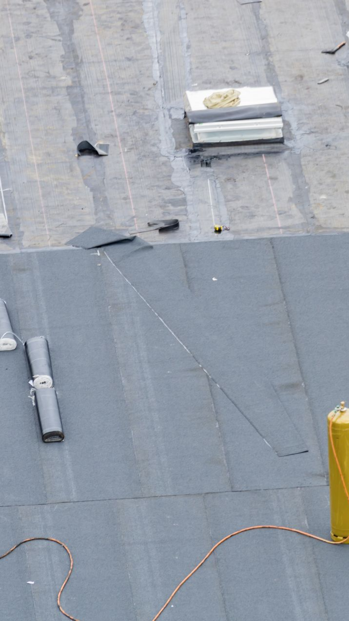 Toiture à la surface gris foncé, avec des équipements et un cylindre jaune.