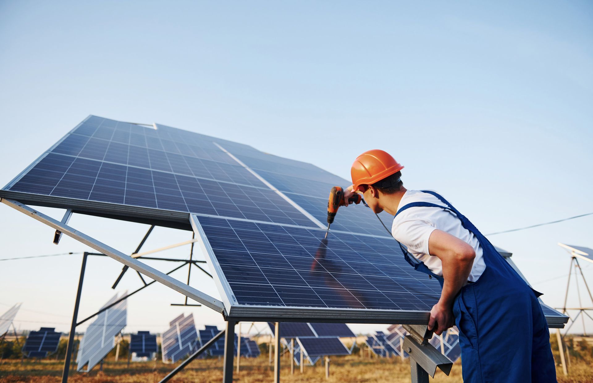 Un hombre está trabajando en un panel solar con un taladro.