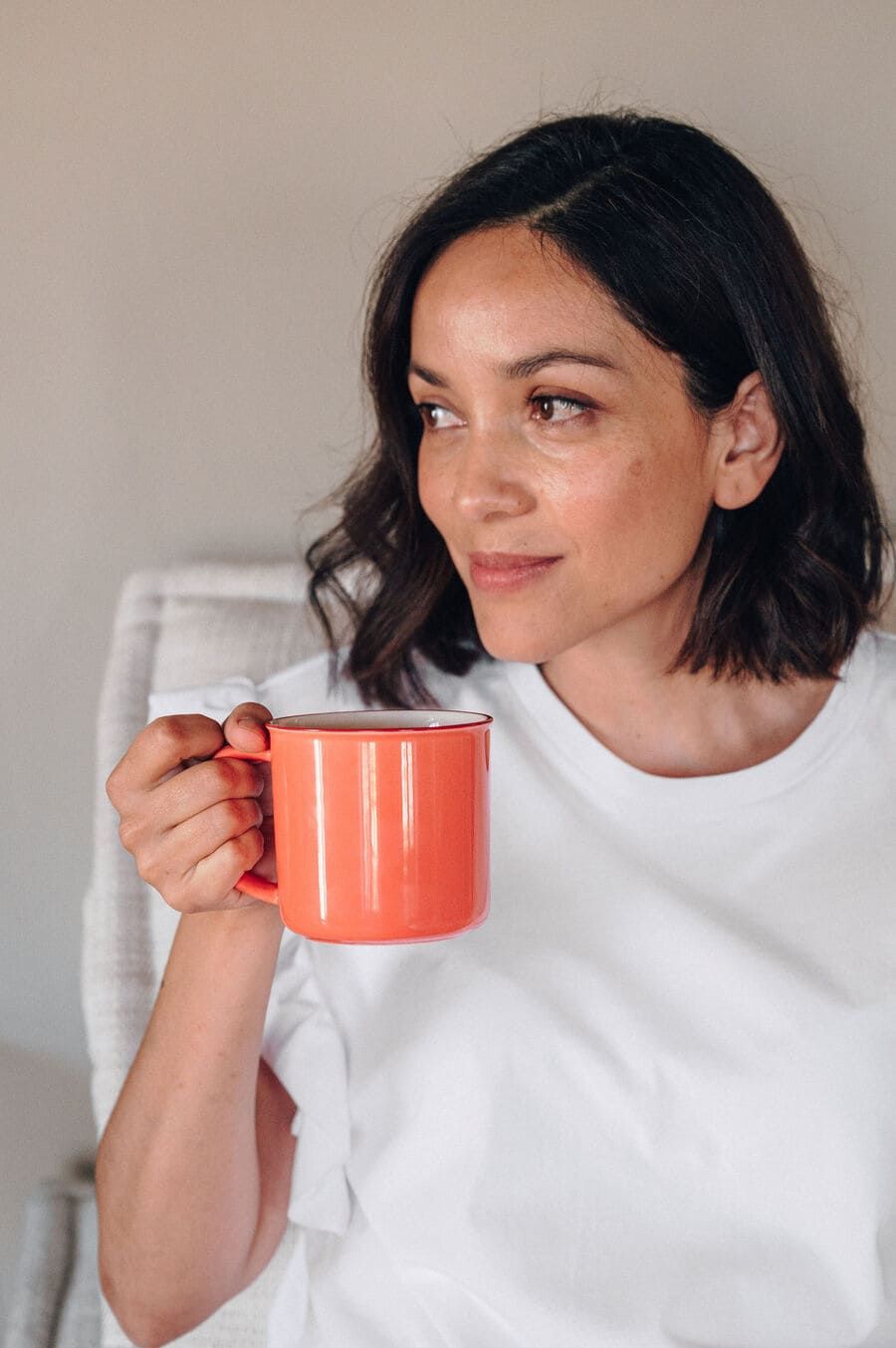 Una mujer está sentada en una silla sosteniendo una taza de café.