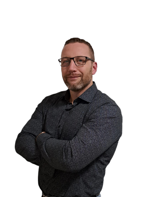 Mann mit Bart in einer blau-schwarzen Jacke, der sich an eine weisse Fläche lehnt.