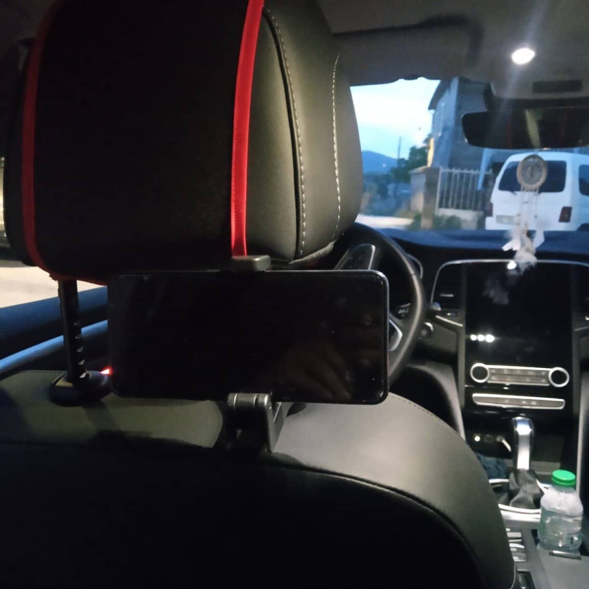 Reposacabezas negro de coche con teléfono. Correa roja en el reposacabezas. Foto del interior.