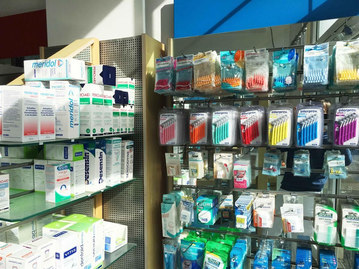 Regale mit verschiedenen Zahnhygieneprodukten in einem Geschäft, darunter Zahnbürsten, Interdentalbürsten und Mundwasser.