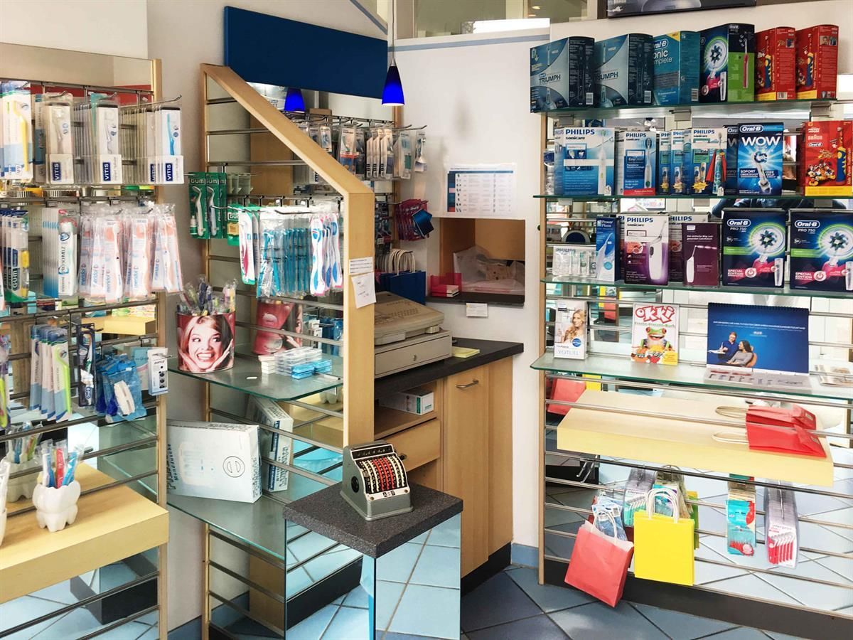 Innenansicht eines kleinen Einzelhandelsgeschäfts mit Regalen, in denen verschiedene Gesundheits- und Schönheitsprodukte ausgestellt sind. Eine Registrierkasse und eine Theke sind sichtbar.