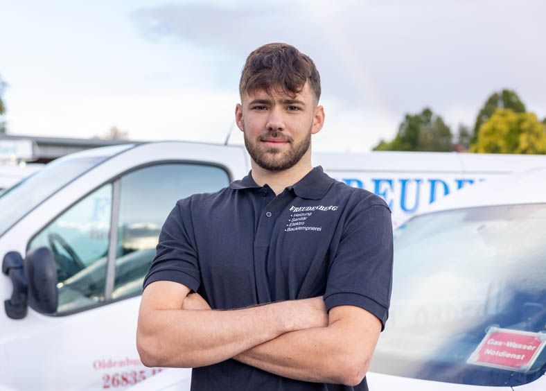 Ein Mann mit verschränkten Armen steht vor einem weißen Lieferwagen.