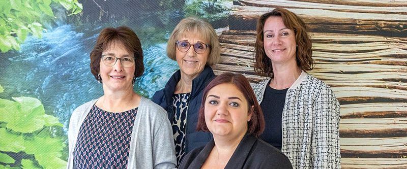 Eine Gruppe von Frauen posiert vor einer Holzwand für ein Foto.