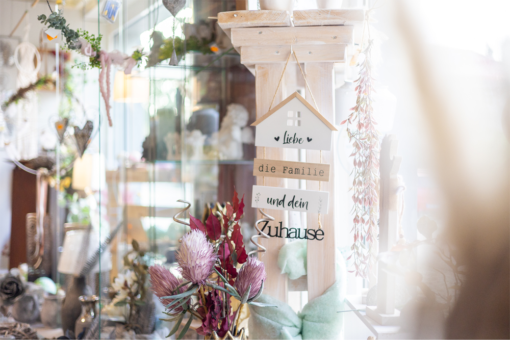 Eine Vase mit Blumen steht auf einem Tisch neben einem Holzschild.
