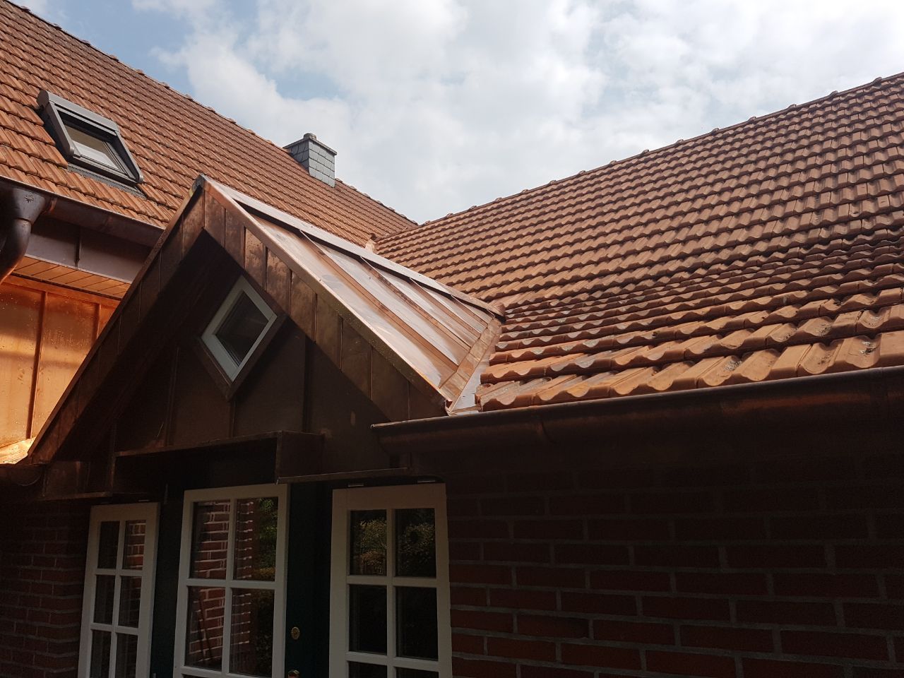 Ein Backsteinhaus mit einem Kupferdach und einem Fenster