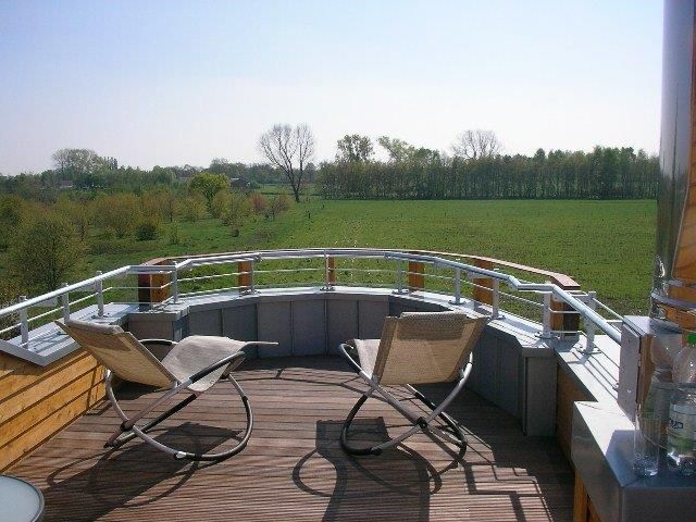 Eine Terrasse mit Stühlen und einem Tisch mit Blick auf ein Feld
