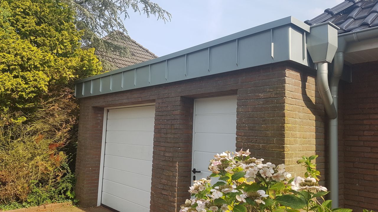 Eine gemauerte Garage mit einer weißen Tür und einem grünen Dach