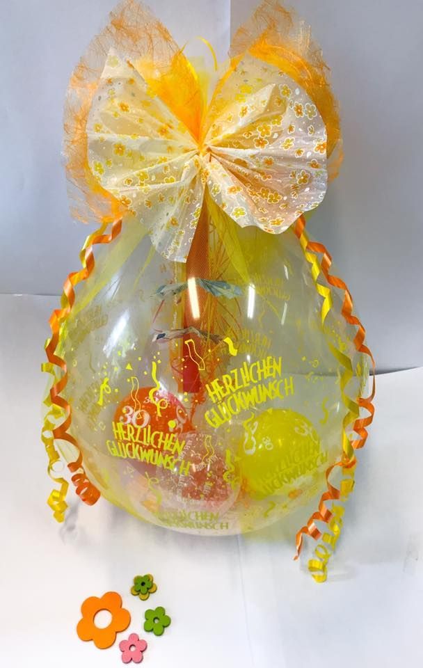 Ein durchsichtiger Ballon mit einer gelben Schleife und Blumen darauf