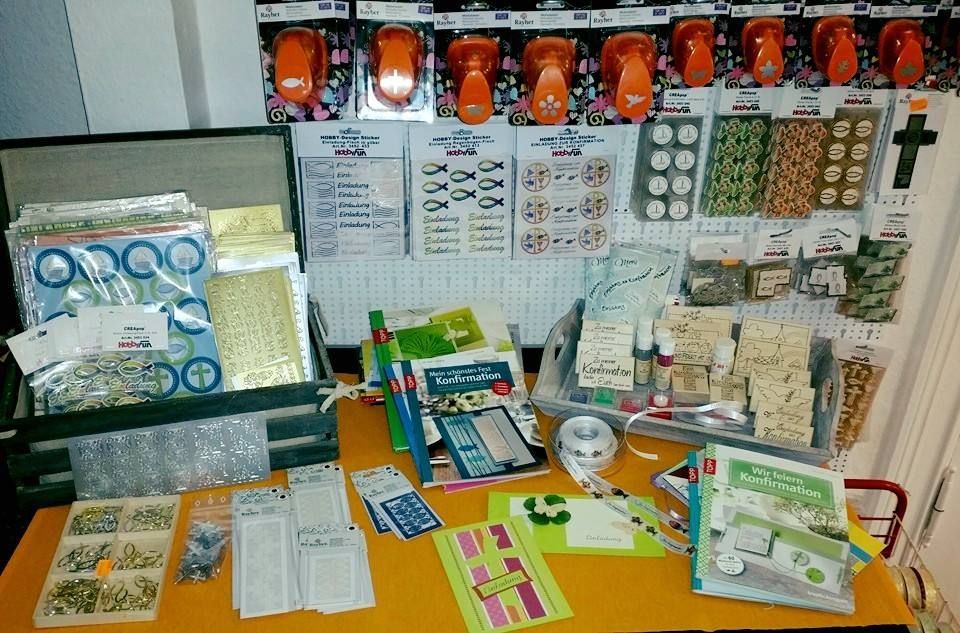 Ein Tisch voller Bastelmaterial mit einem Kreuz an der Wand dahinter