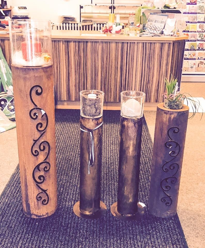 Drei Holzsäulen mit Kerzen darin stehen auf einem Teppich vor einer Theke.