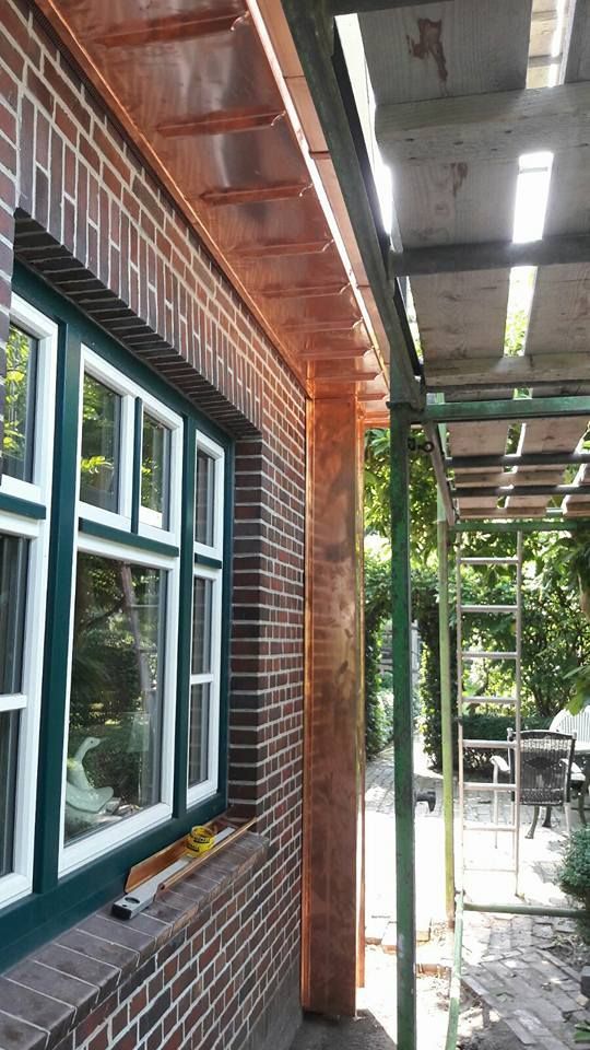 Ein Backsteingebäude mit einem Fenster und einer Kupferdachrinne.