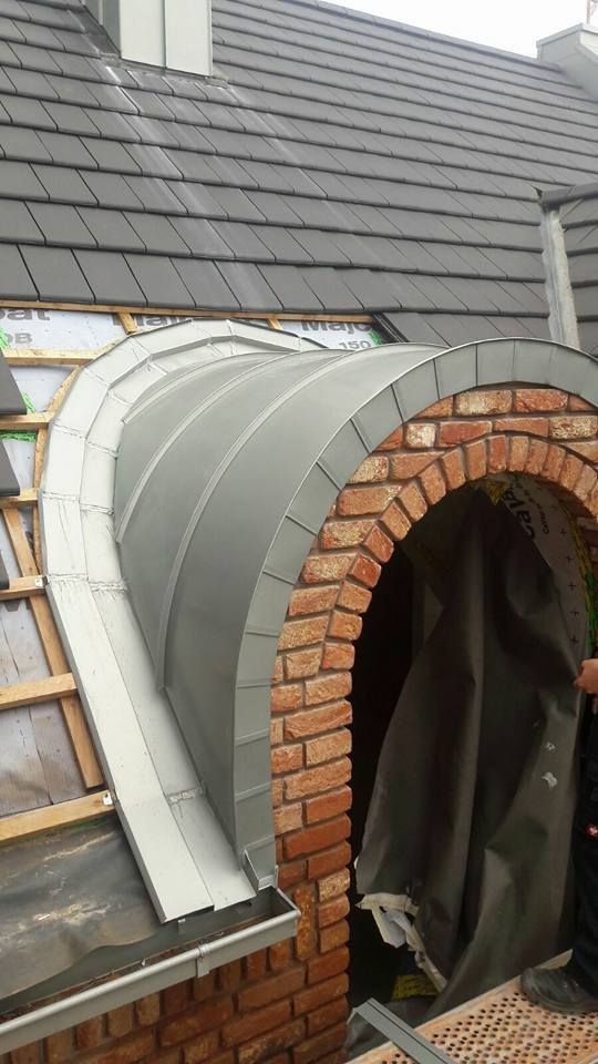 In das Dach eines Hauses wird ein gemauerter Torbogen eingebaut.