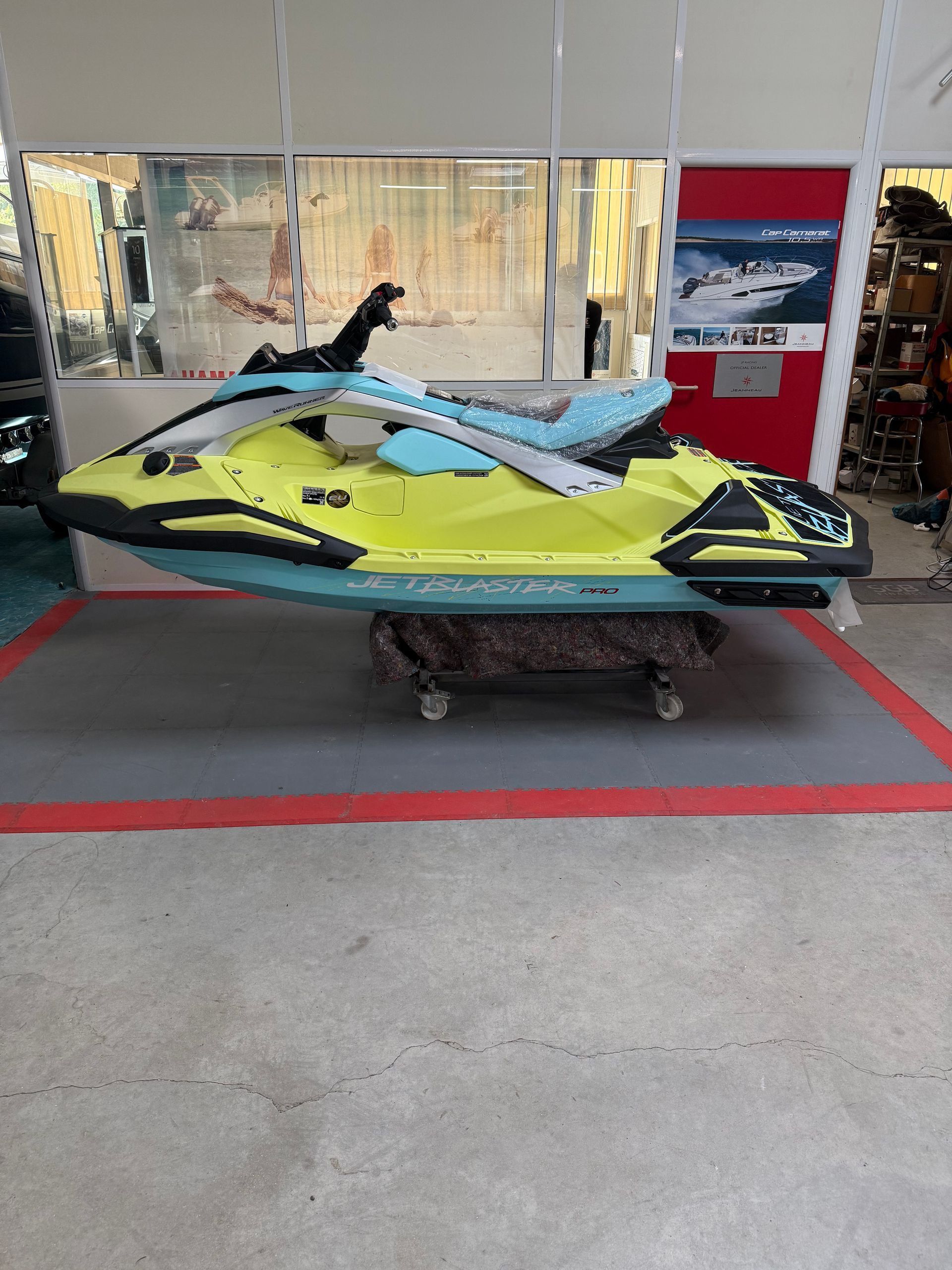 Jet ski jaune et bleu sur un tapis gris dans un décor de magasin.