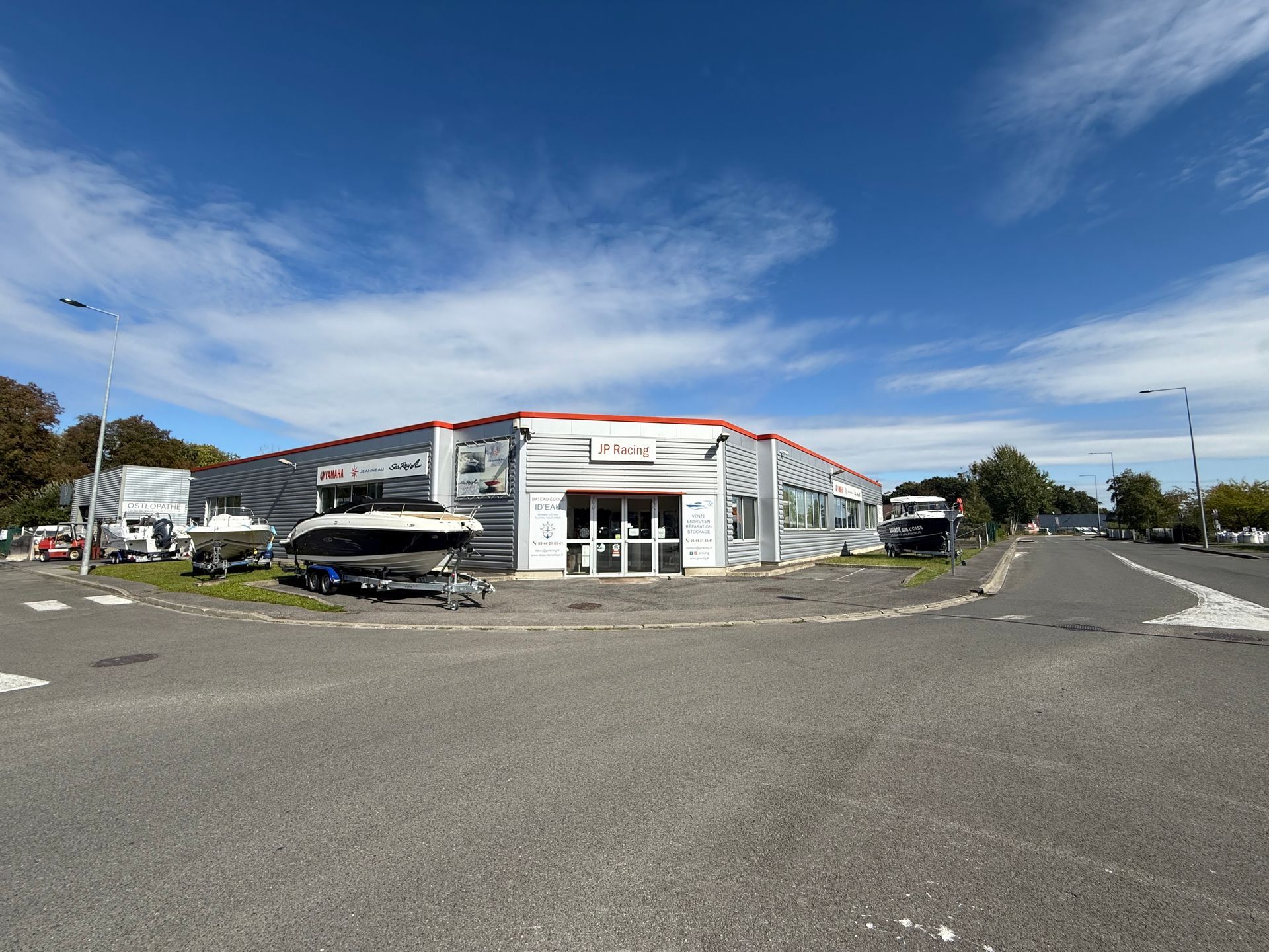 Vue en contre-plongée d'un bâtiment commercial sous un ciel bleu, affichant des bateaux devant.
