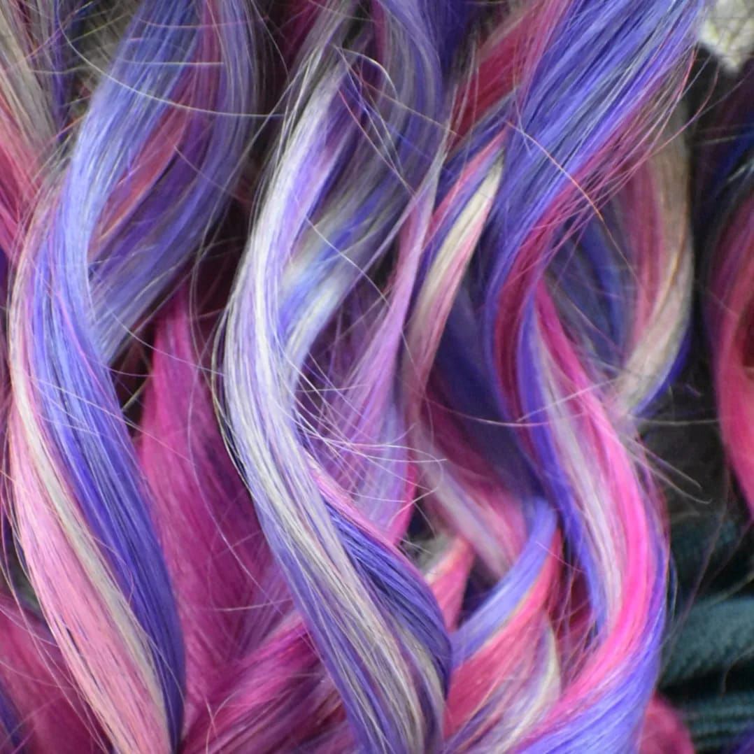 Trenzas de cabello de colores rosa, blanco y morado.