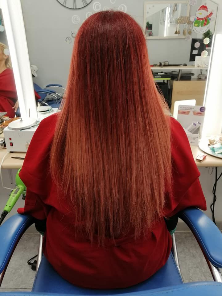 Mujer con el pelo largo y rojo, sentada en una silla de peluquería. El pelo se aclara hacia las puntas.