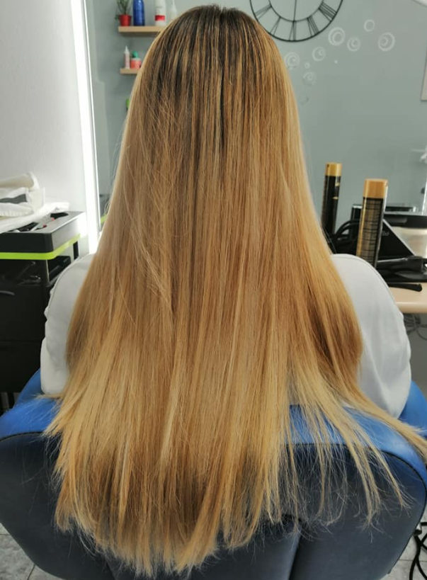 Cabello rubio, hasta los hombros, sentada en una silla de peluquería. El cabello tiene un degradado de color