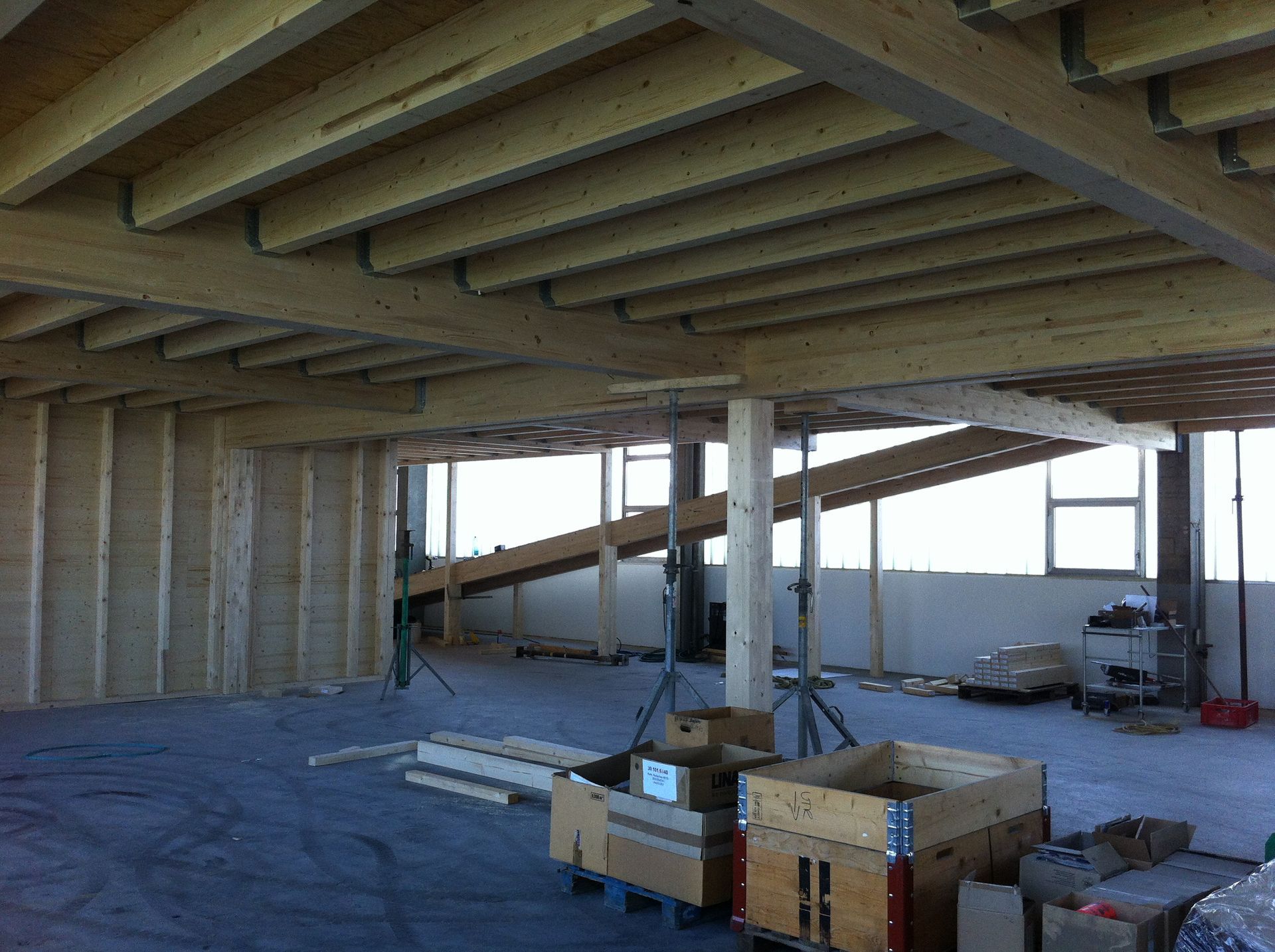 A building under construction with wooden beams and boxes on the floor.
