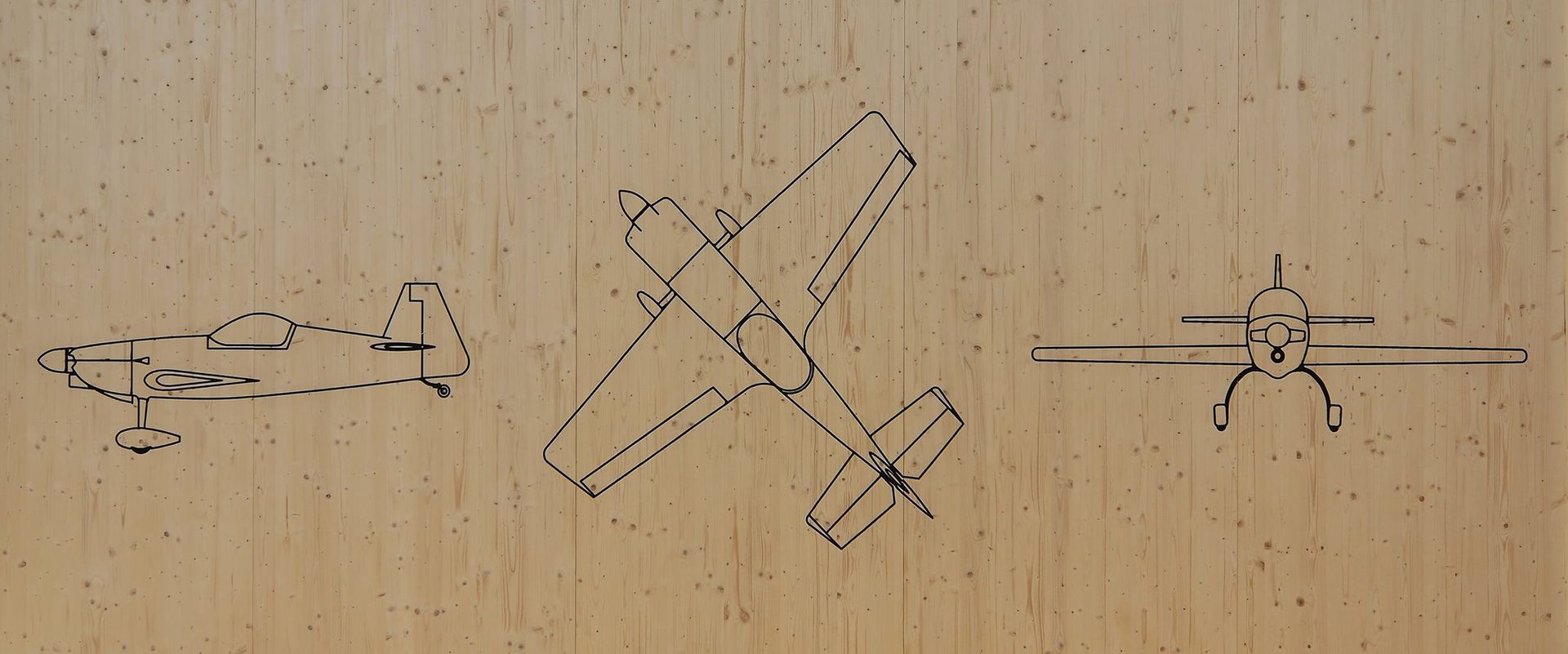 Three drawings of airplanes on a wooden surface