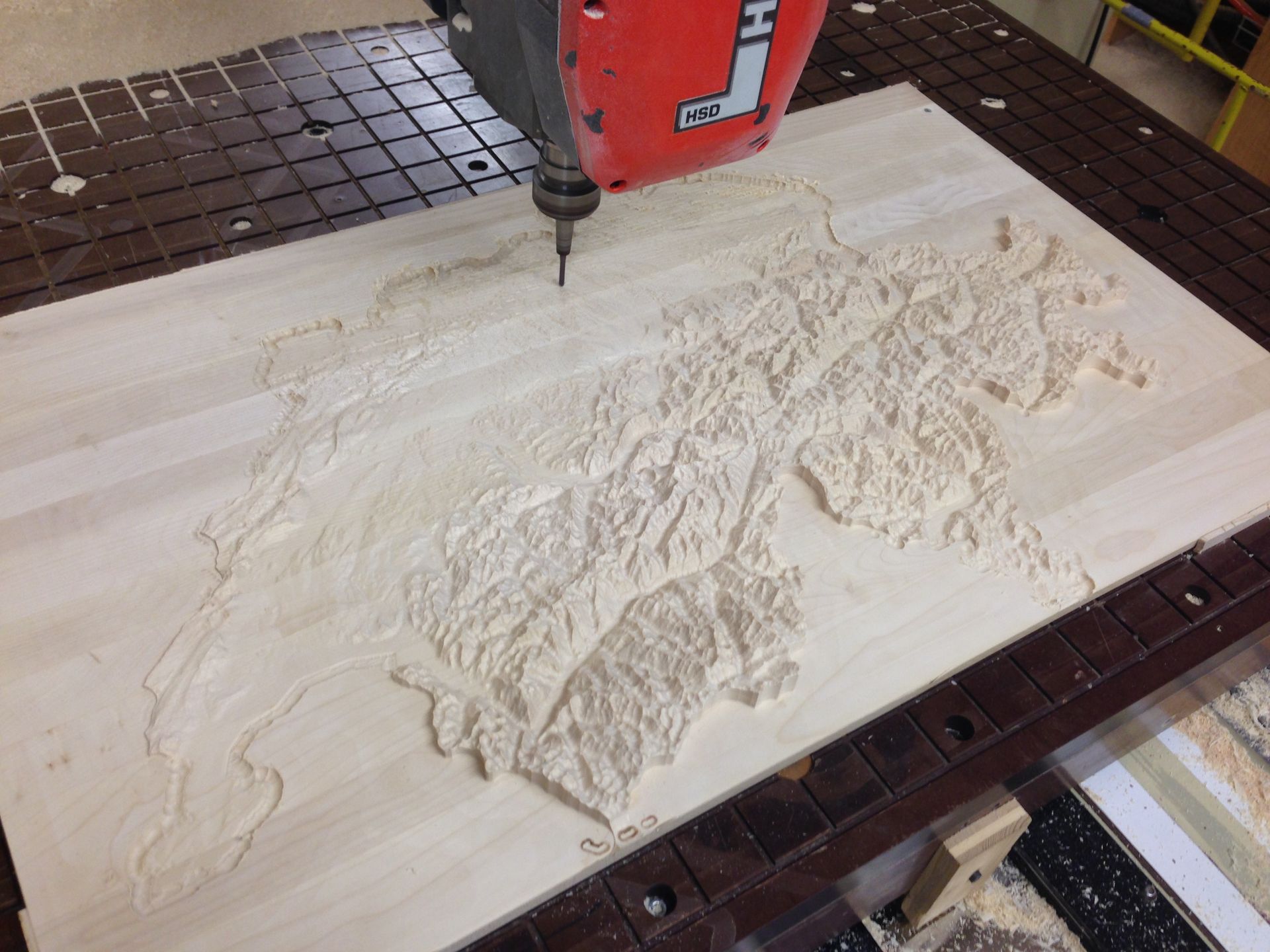A machine is carving a map on a piece of wood